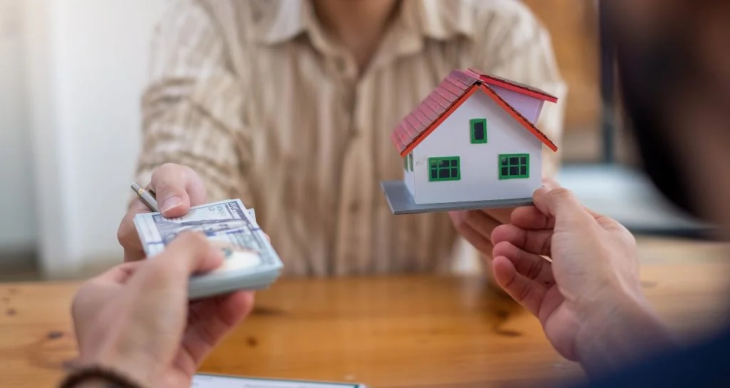 business-people-handing-over-dollars-with-model-house-in-hand